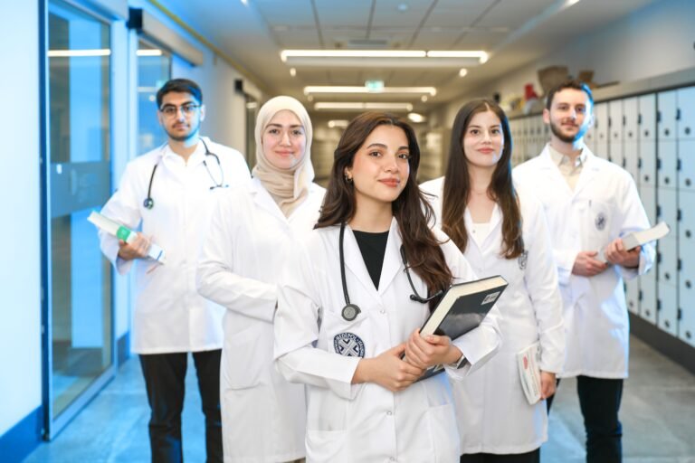 Group of diverse medical students wearing lab coats in university corridor, representing future healthcare professionals.